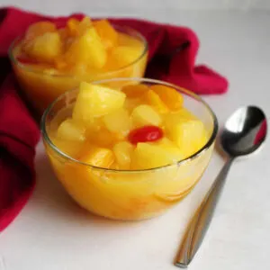 Two small glass bowls filled with fruit salad in a vanilla pudding dressing, ready to eat.