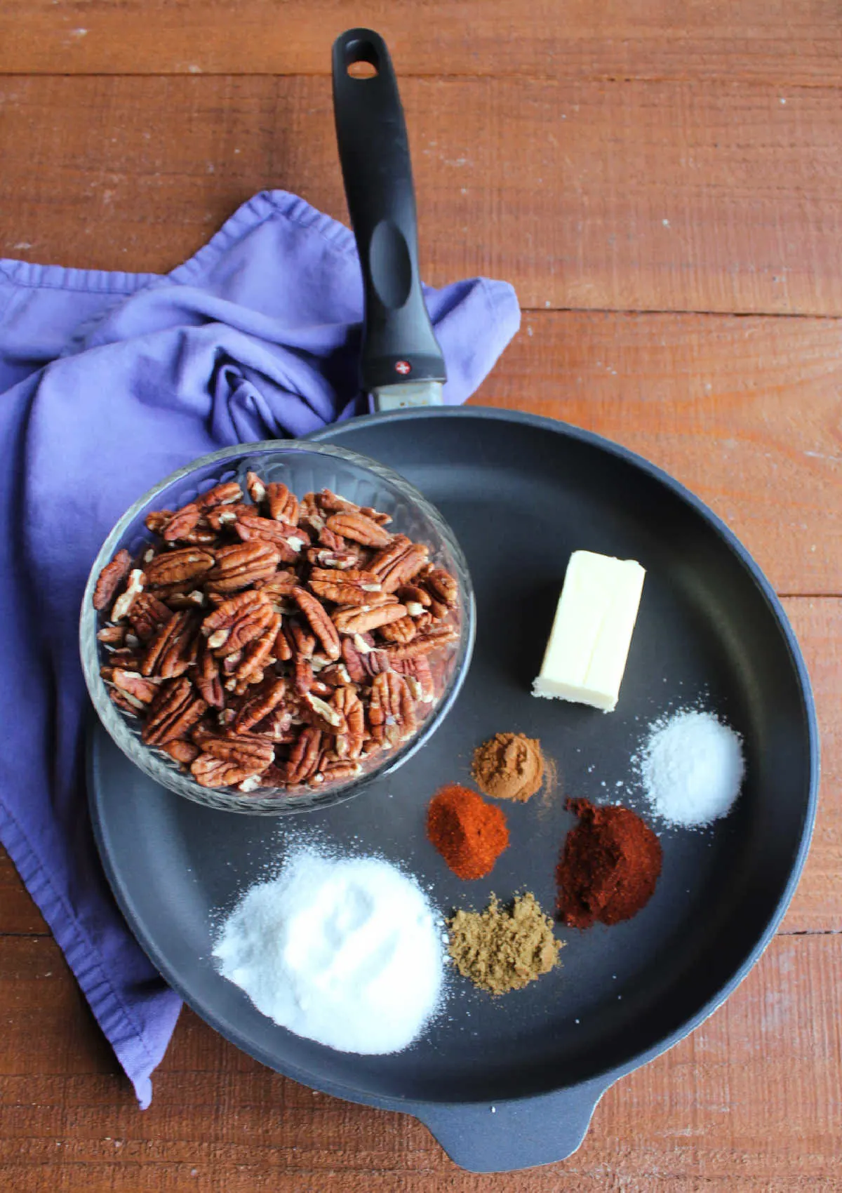 Ingredients in skillet including bowl of pecans, butter, sugar, salt and seasonings.