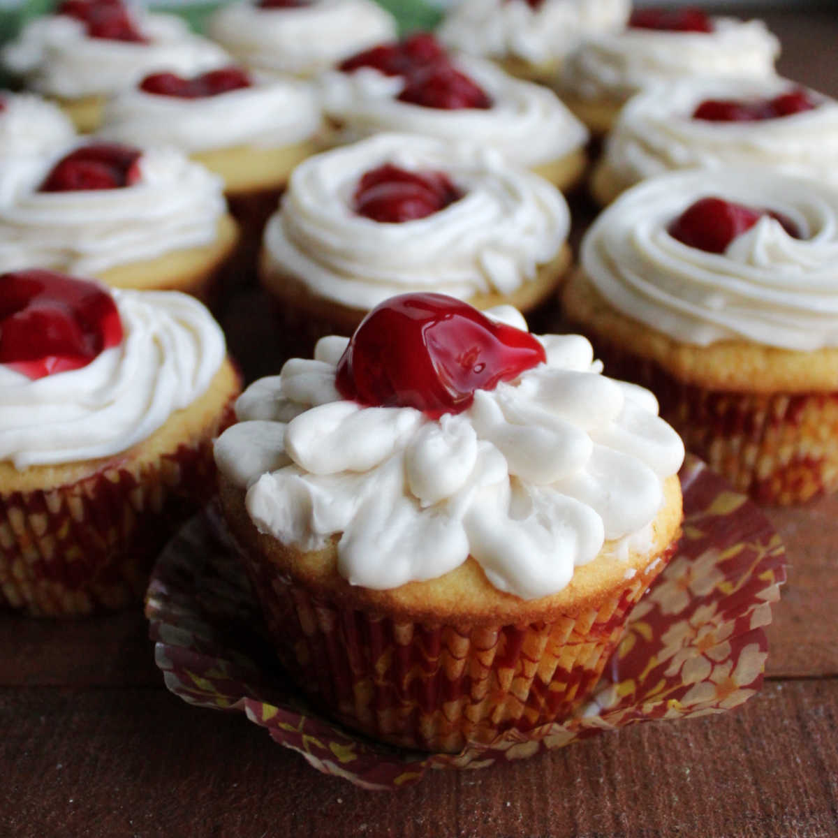 Cupcakes topped with white buttercream frosting and cherry pie filling.