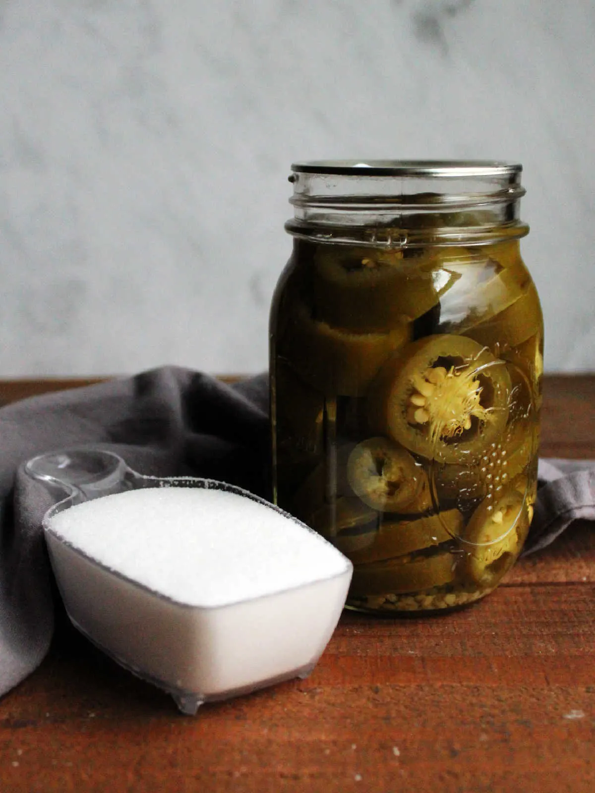 Candied jalapeno ingredients: a jar of pickled jalapenos and white sugar.