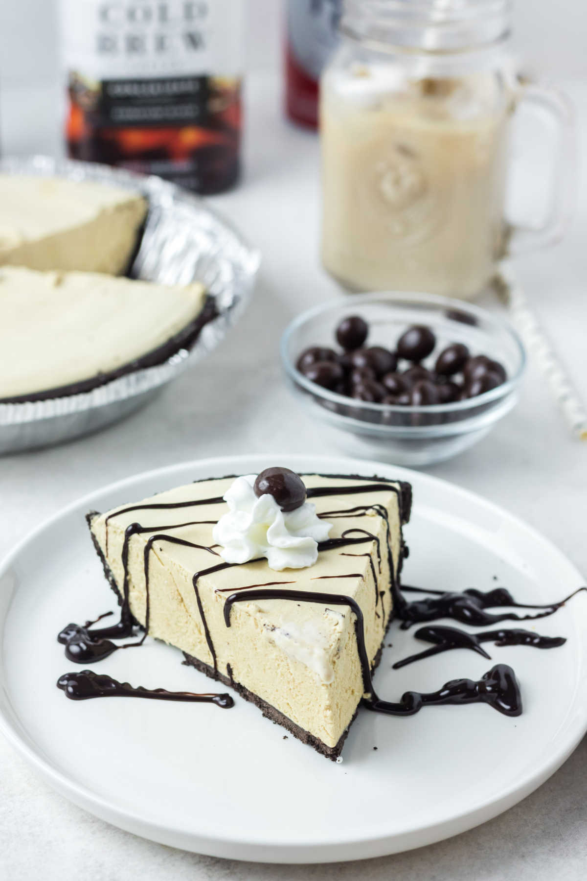 Slice of frozen coffee pie drizzled with dark chocolate fudge sauce, ready to eat.