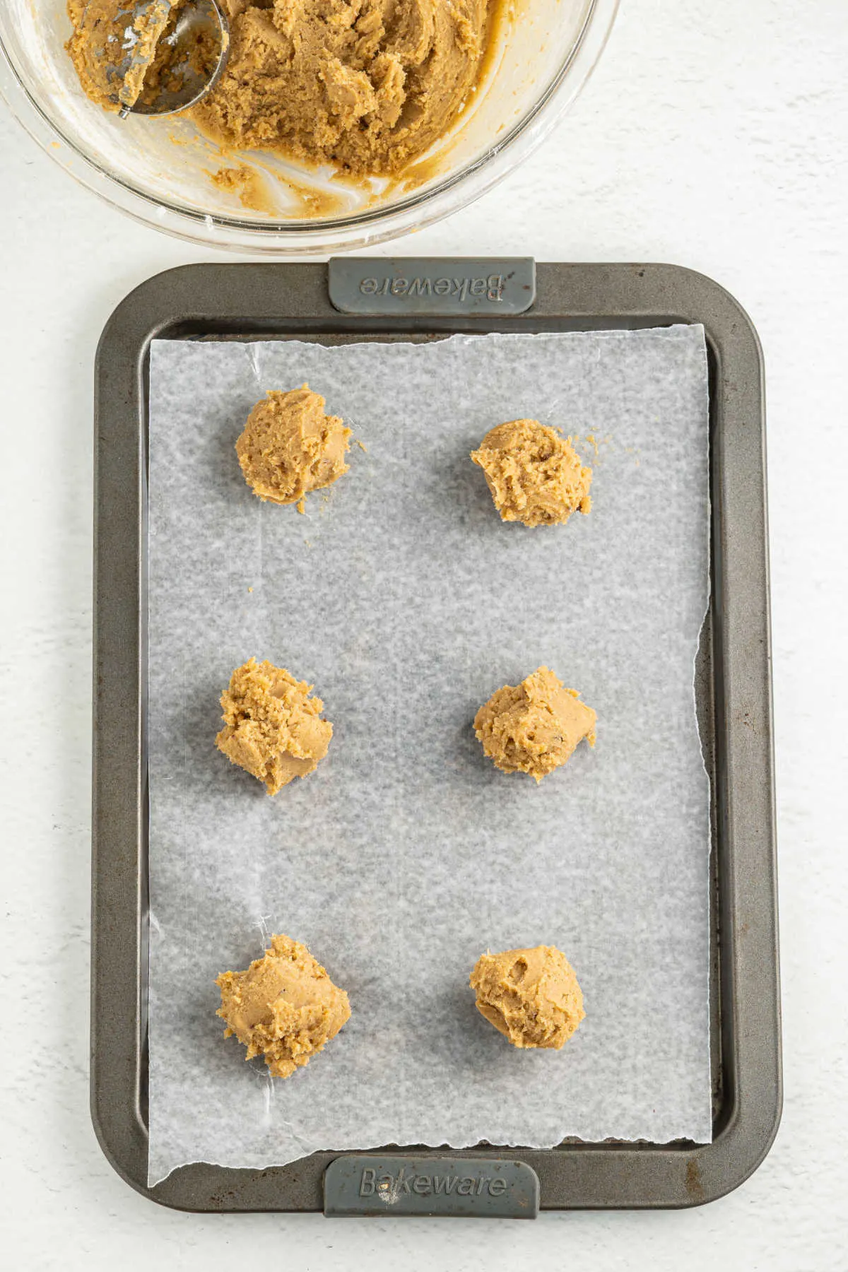 Scoops of chai cookie dough on a parchment lined cookie sheet, ready to bake. 