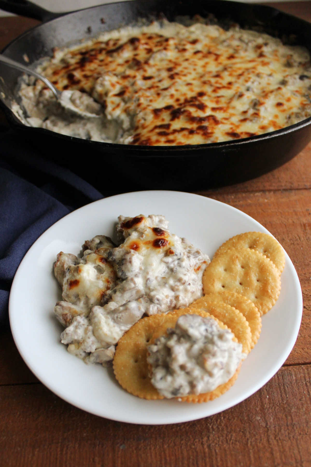 Stuffed mushroom dip served on small dip with crackers, ready to eat.