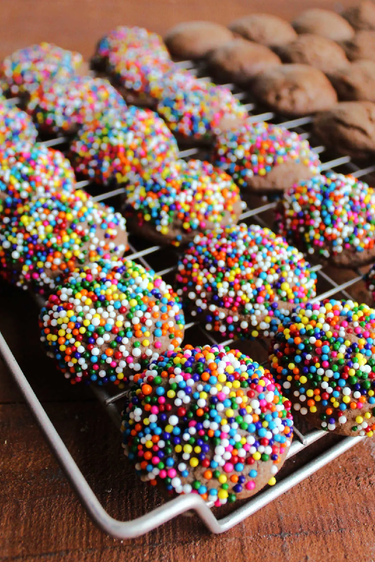 Sprinkle coated chocolate cookies on wire cooling rack.