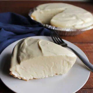 Slice of smooth and creamy orange pie in graham cracker crust with remaining pie in the background.