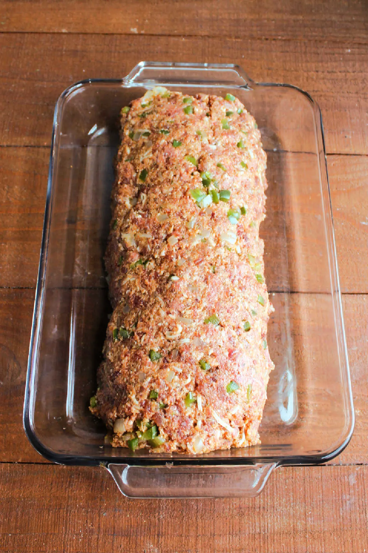 Formed meatloaf made from beef, sausage, peppers, onions and more made into a loaf in a 9x13-inch pan.
