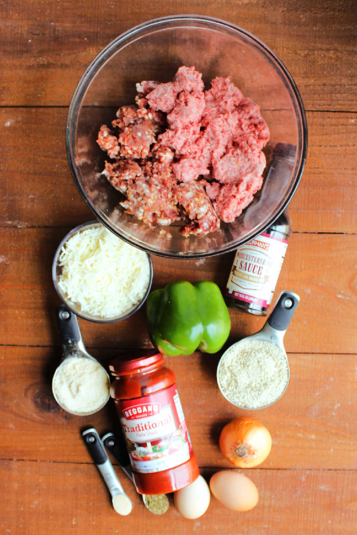 Ingredients including ground beef, Italian sausage, bell pepper, onion, eggs, bread crumbs, marinara sauce and Worcestershire sauce ready to be made into Italian meatloaf.