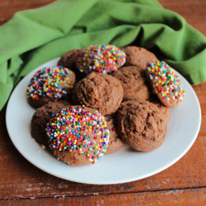 Plate filled with chocolate condensed milk cookies, some plain and others coated in colorful sprinkles.