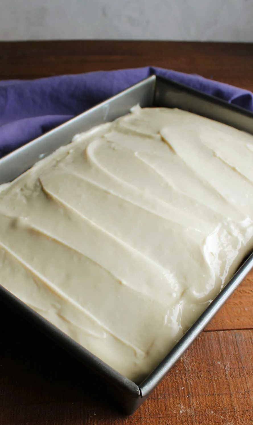 Lemon cream cheese frosting spread over cake in a 9x13-inch pan.