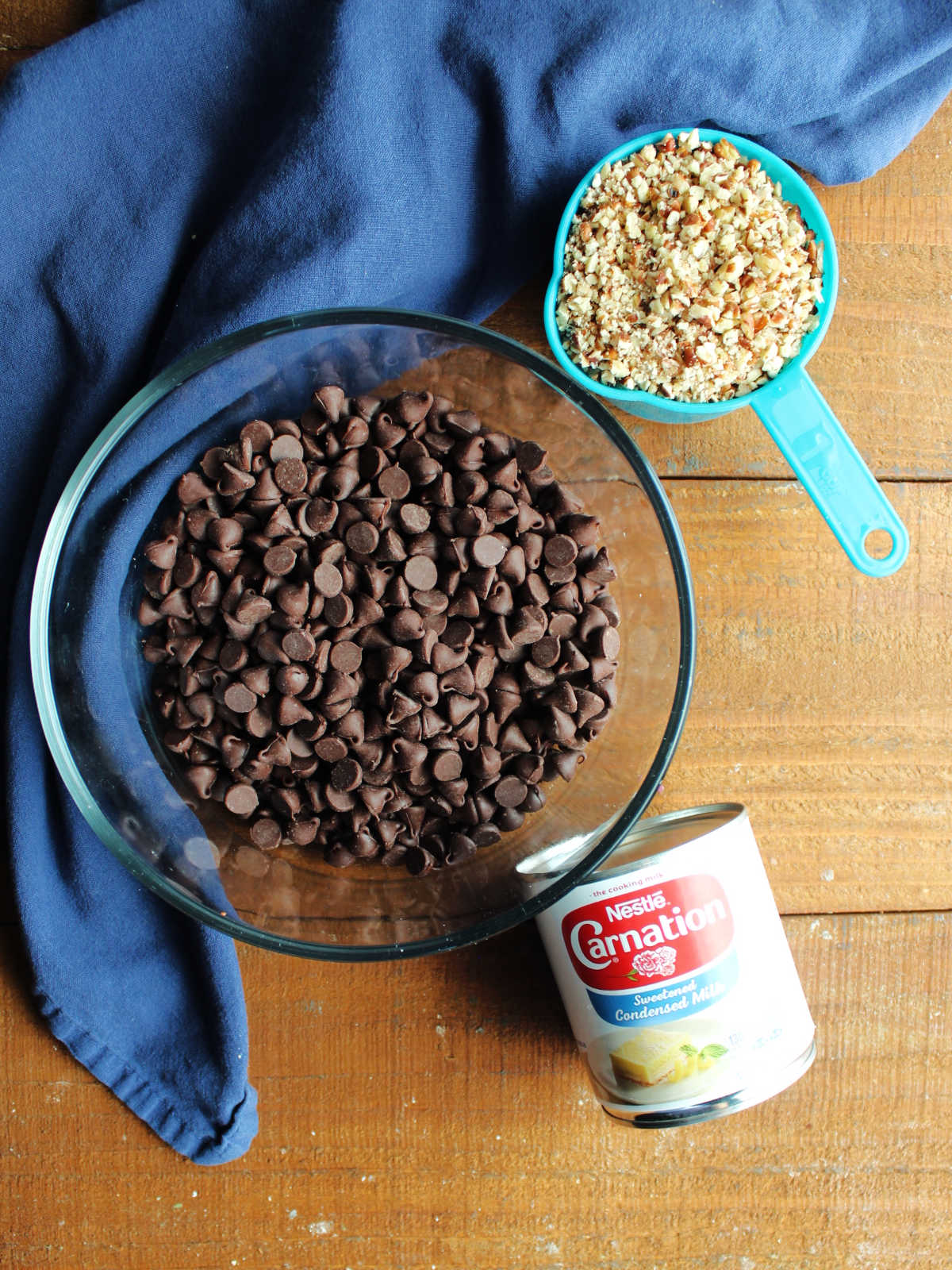 Ingredients including chocolate chips, condensed milk, and chopped pecans ready to be made into fudge ice cream cups.
