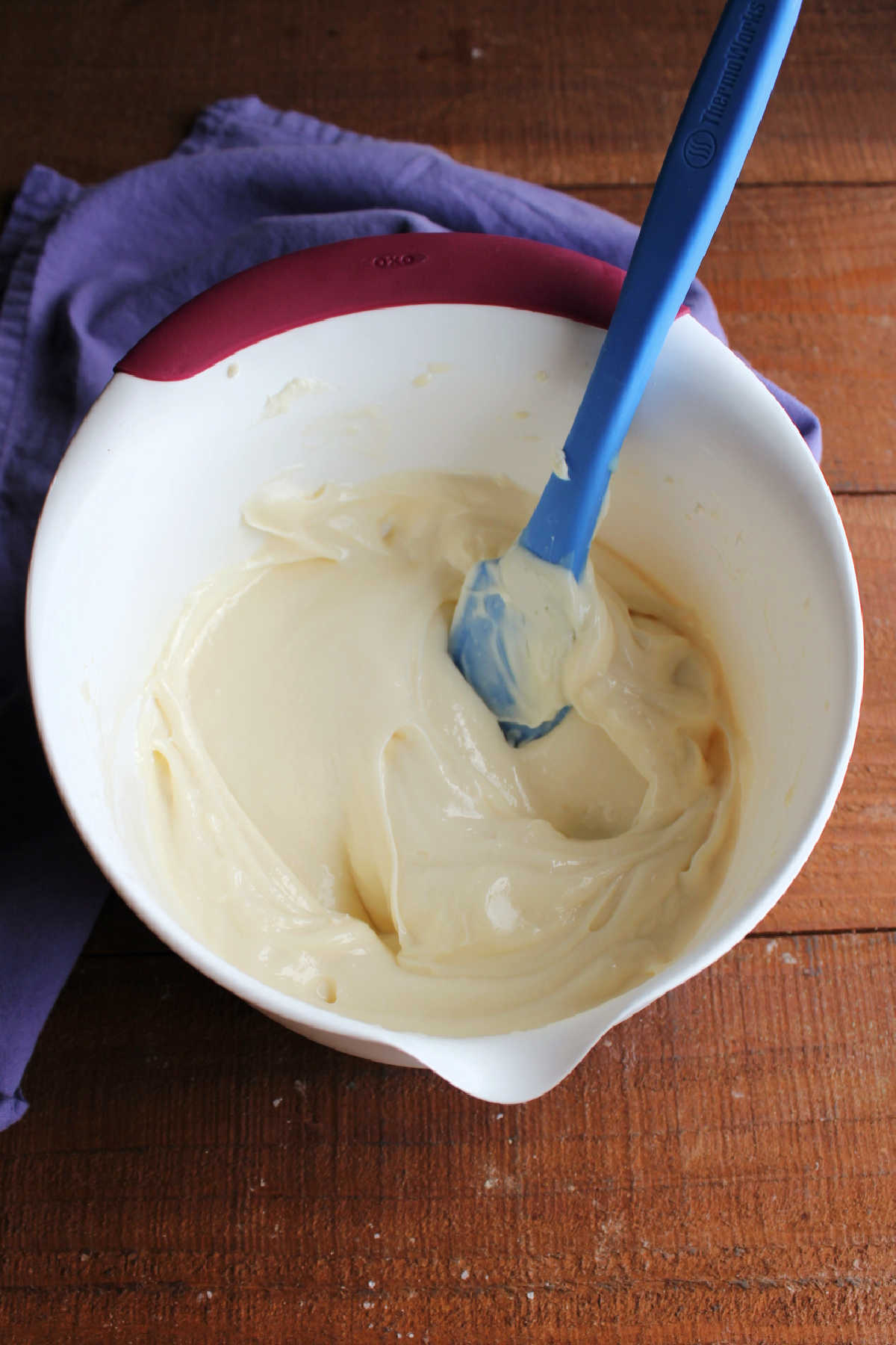 Mixing bowl of chilled lemon cream cheese frosting showing how it is thicker and now holds its ridges when a spatula is run over it.