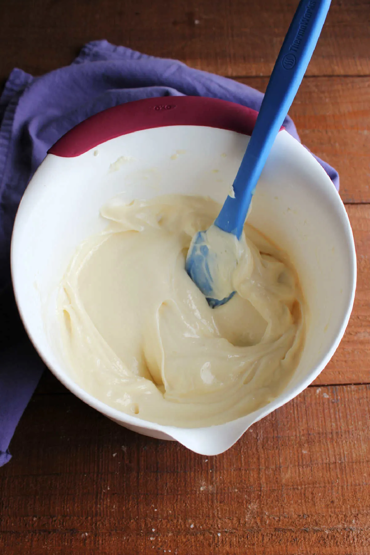 Mixing bowl of chilled lemon cream cheese frosting showing how it is thicker and now holds its ridges when a spatula is run over it.
