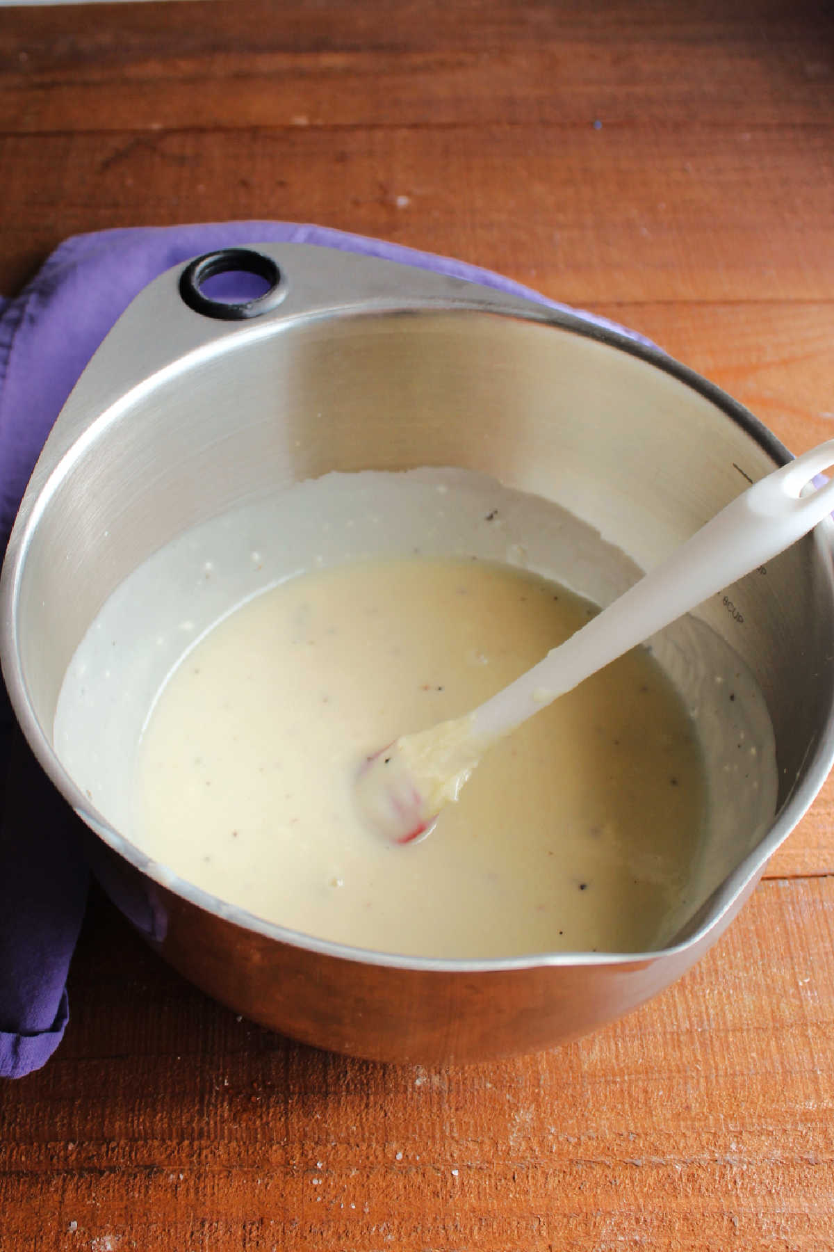 Large mixing bowl with creamy dressing made from condensed milk, mayonnaise, vinegar, sugar, salt and pepper.