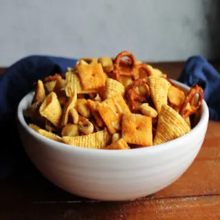 Bowl of ranch snack mix with melted Parmesan cheese on all of the crackers, bugles, pretzels, and nuts.