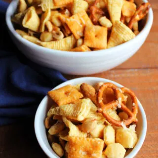 Serving of Parmesan ranch snack mix in front of large bowl of snack mix, showing all of the flavorful crunchy bits inside.