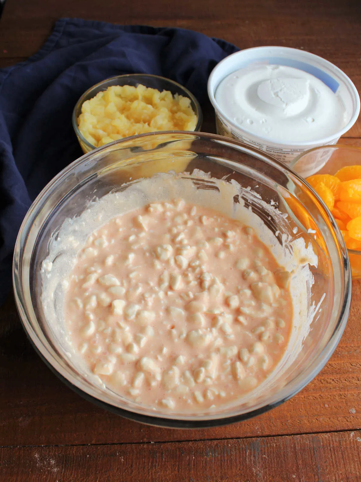 Mixing bowl with orange jello powder mixed into cottage cheese, showing orange hue.
