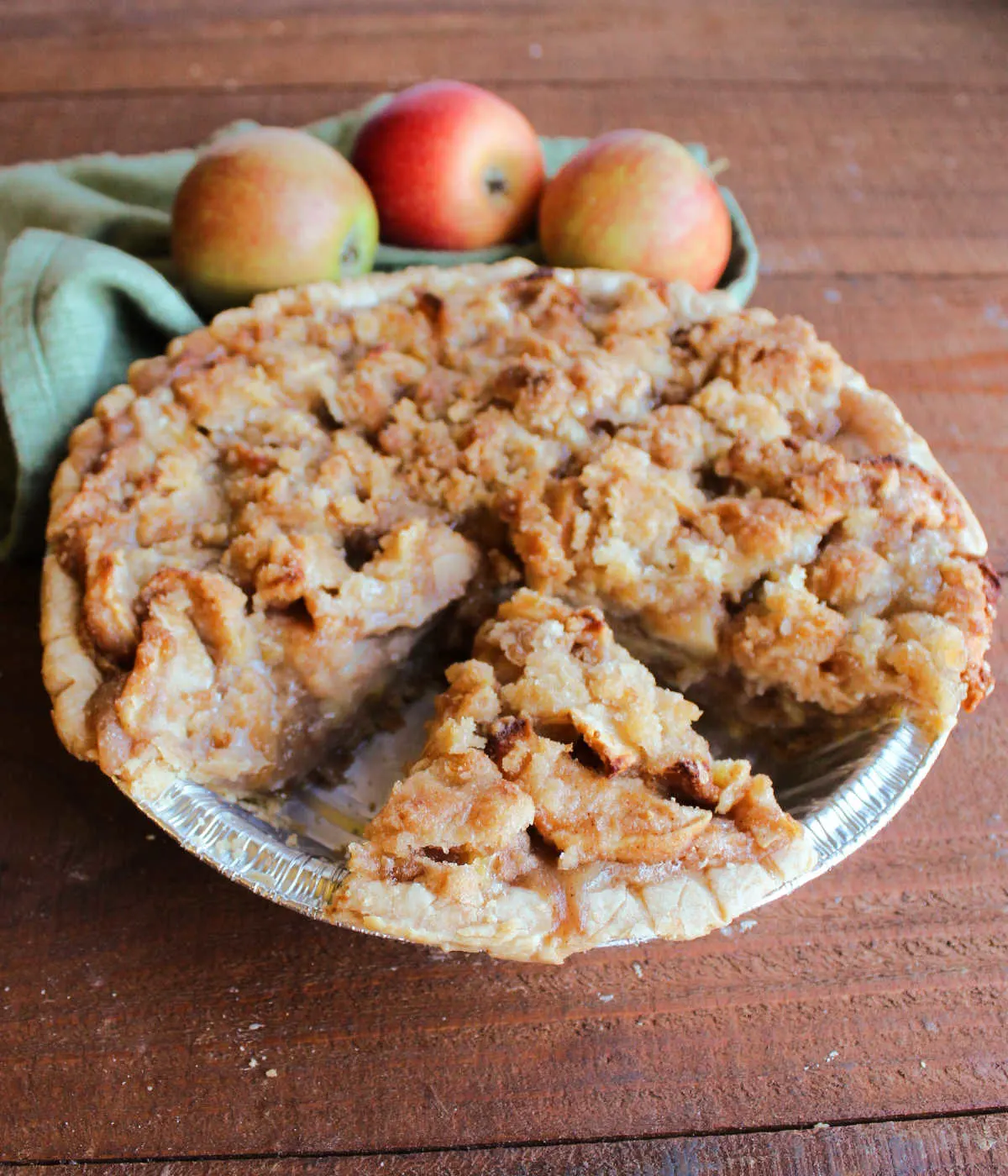 Baked apple pie with buttery crumb mixture on top, one slice missing.