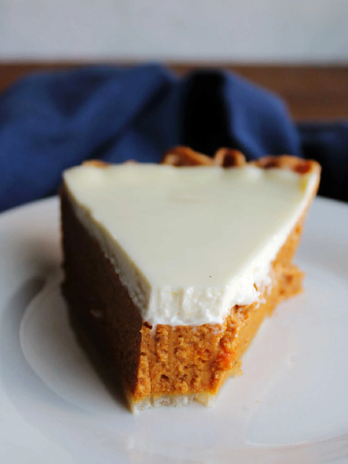 Bite missing from the end of a piece of layered pumpkin pie with sour cream topping. 
