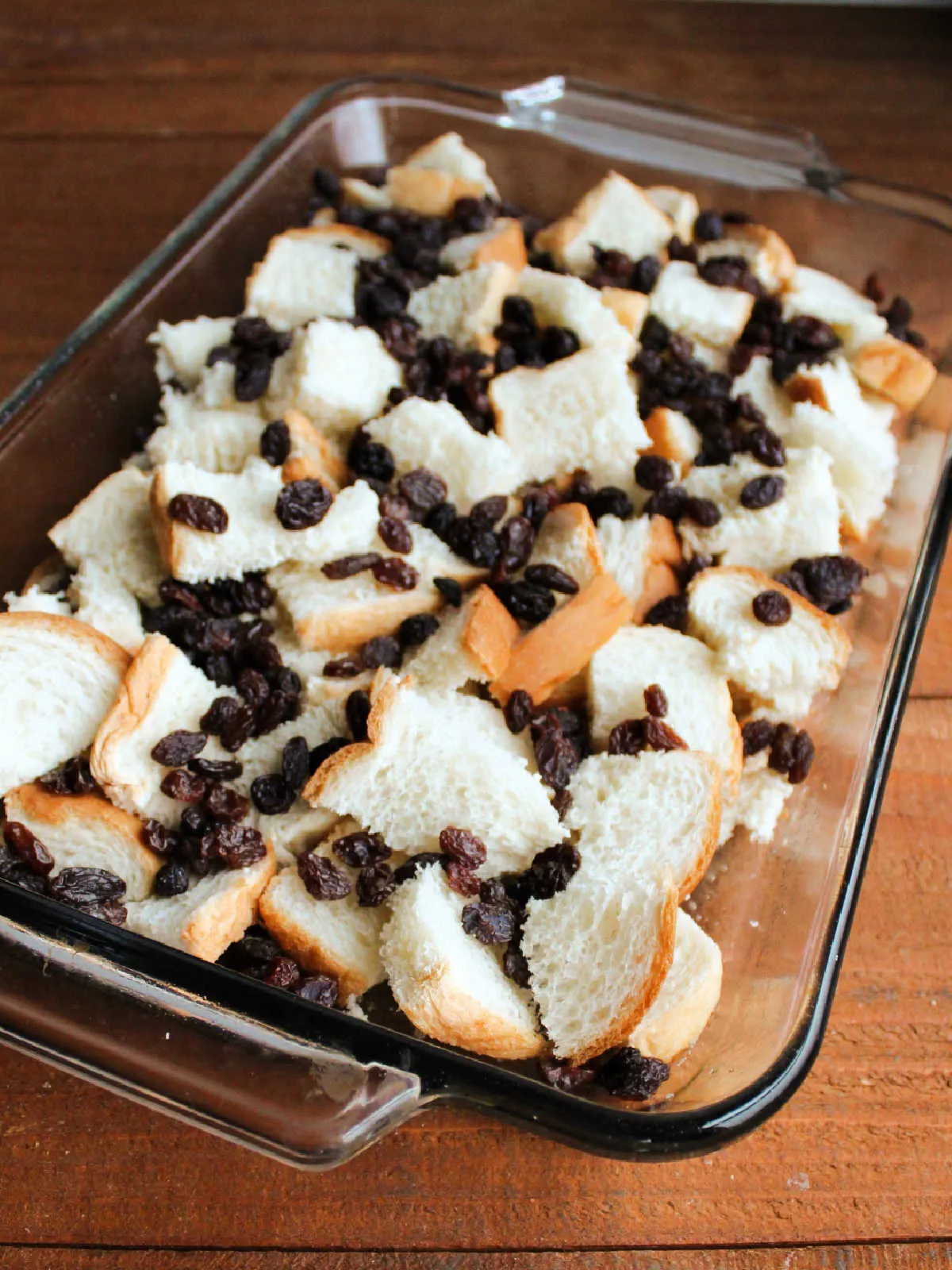 Cubes of stale bread and raisins in 9x13-inch pan.