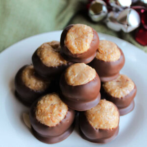 Stack of caramel peanut balls showing centers made from tiny bits of peanuts in caramel mixture dipped in chocolate leaving some of the center showing.