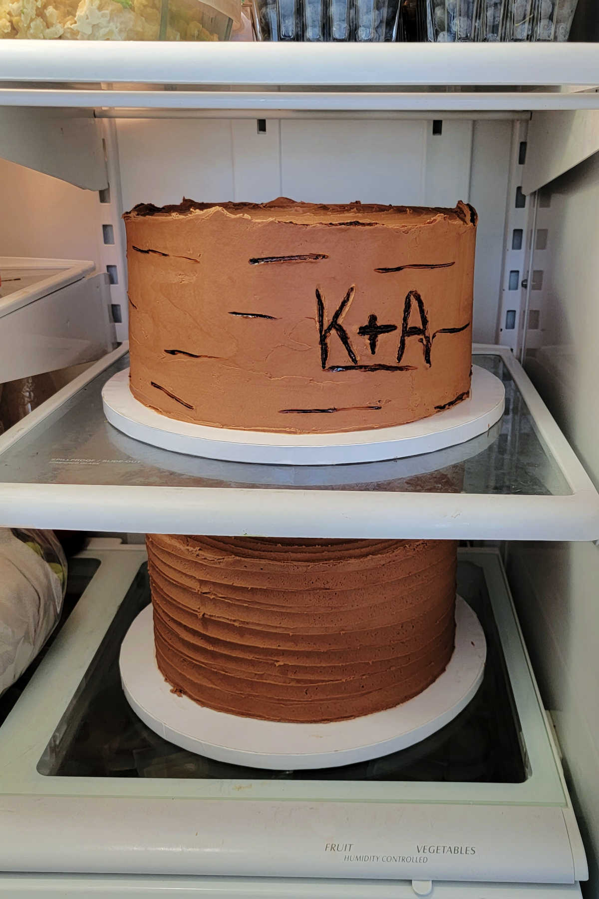 Two 10 inch chocolate cakes chilling in the refrigerator.