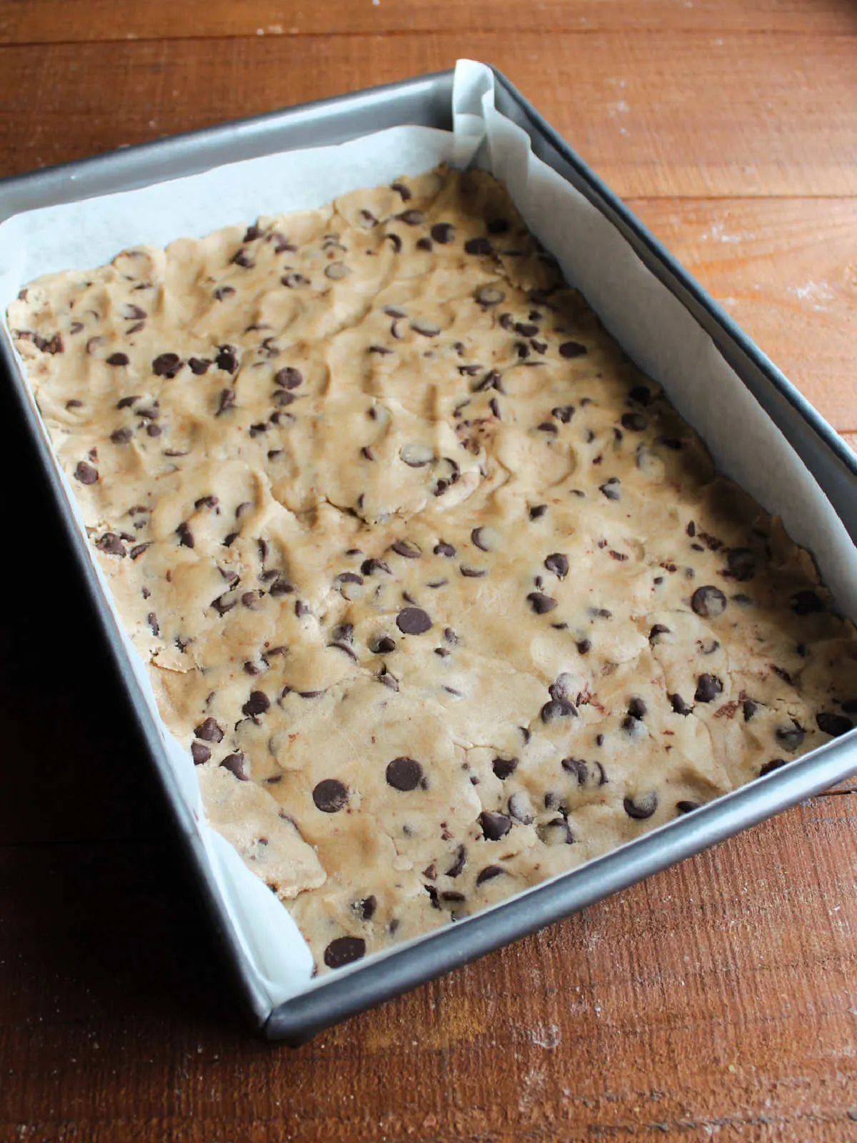 Chocolate chip cookie dough spread on the bottom of a 9x13-inch pan to form a crust. 