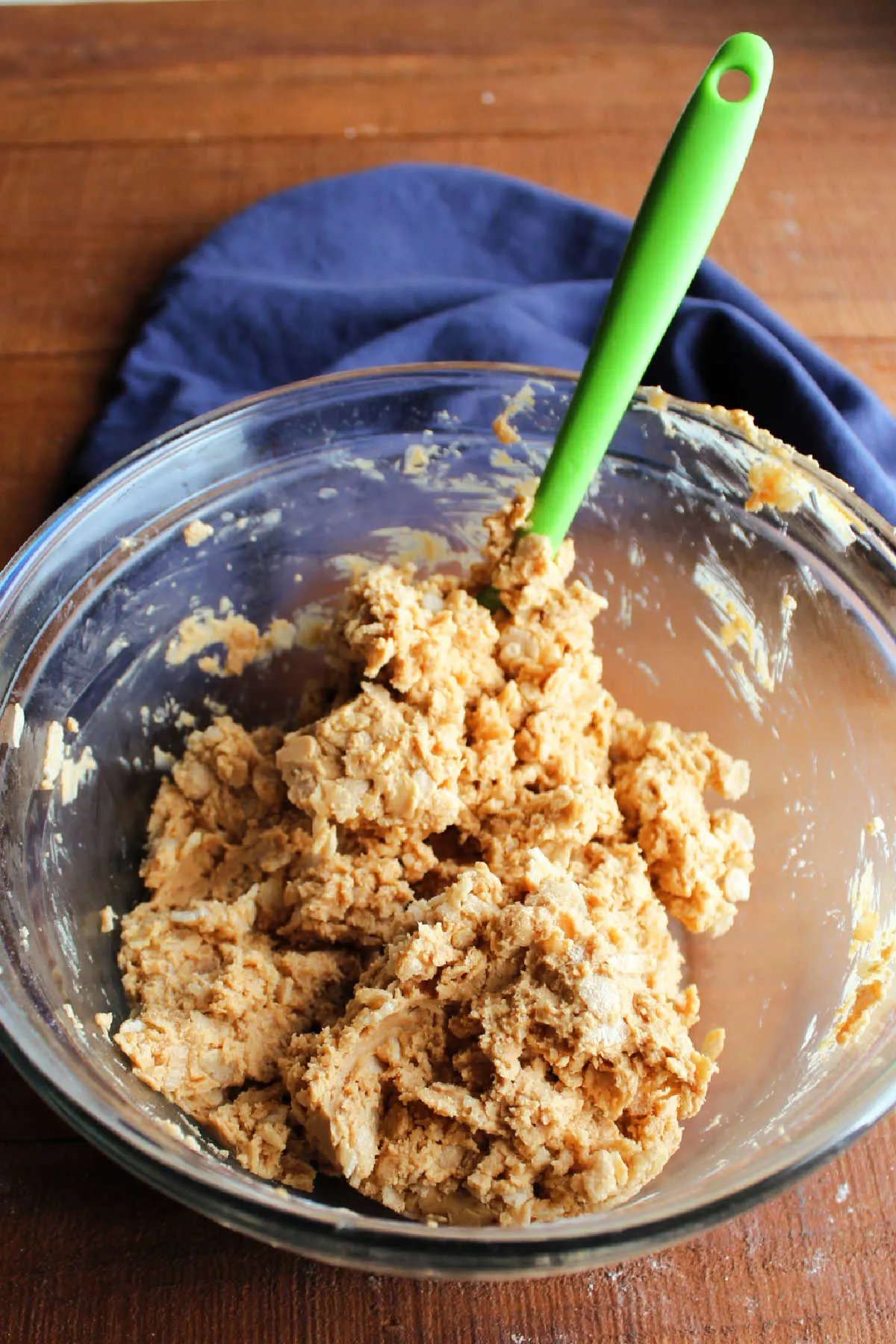 Mixing bowl with spatula folding crisp rice cereal into the peanut butter mixture.
