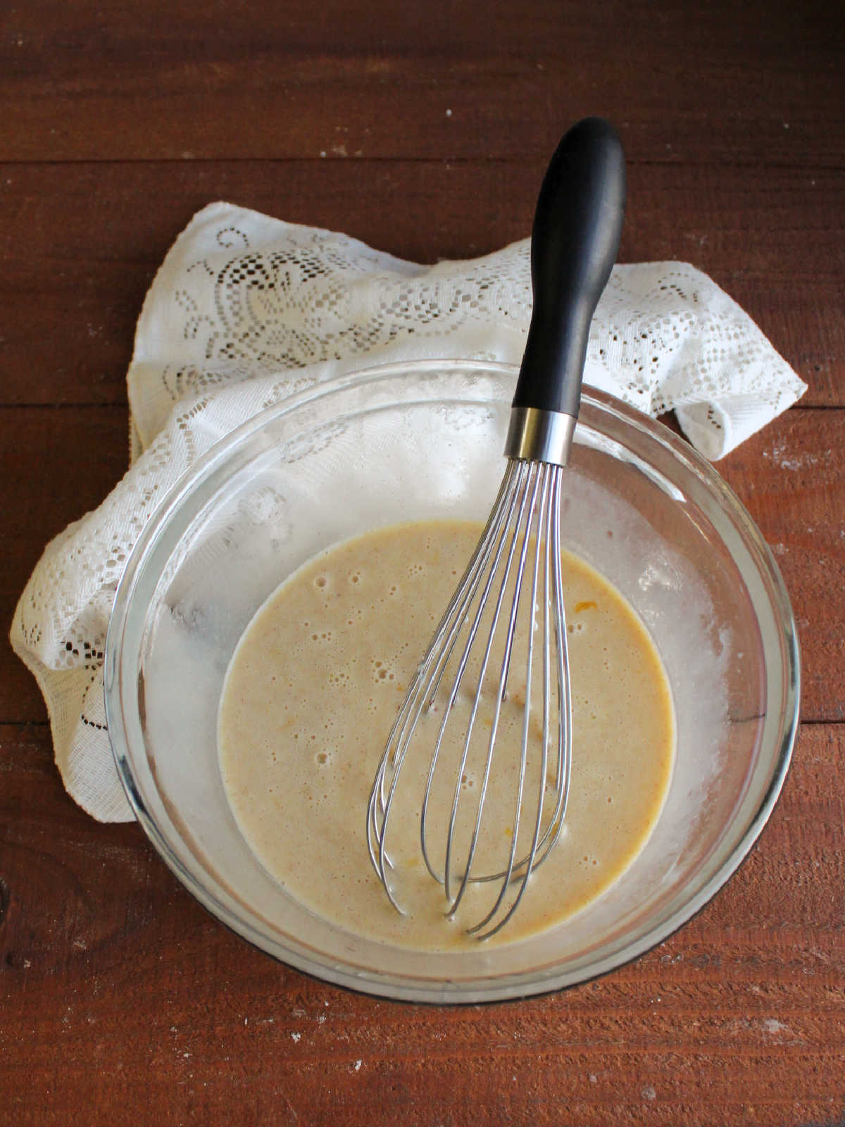 Mixing bowl filled with condensed milk custard mixture with flecks of cinnamon inside.