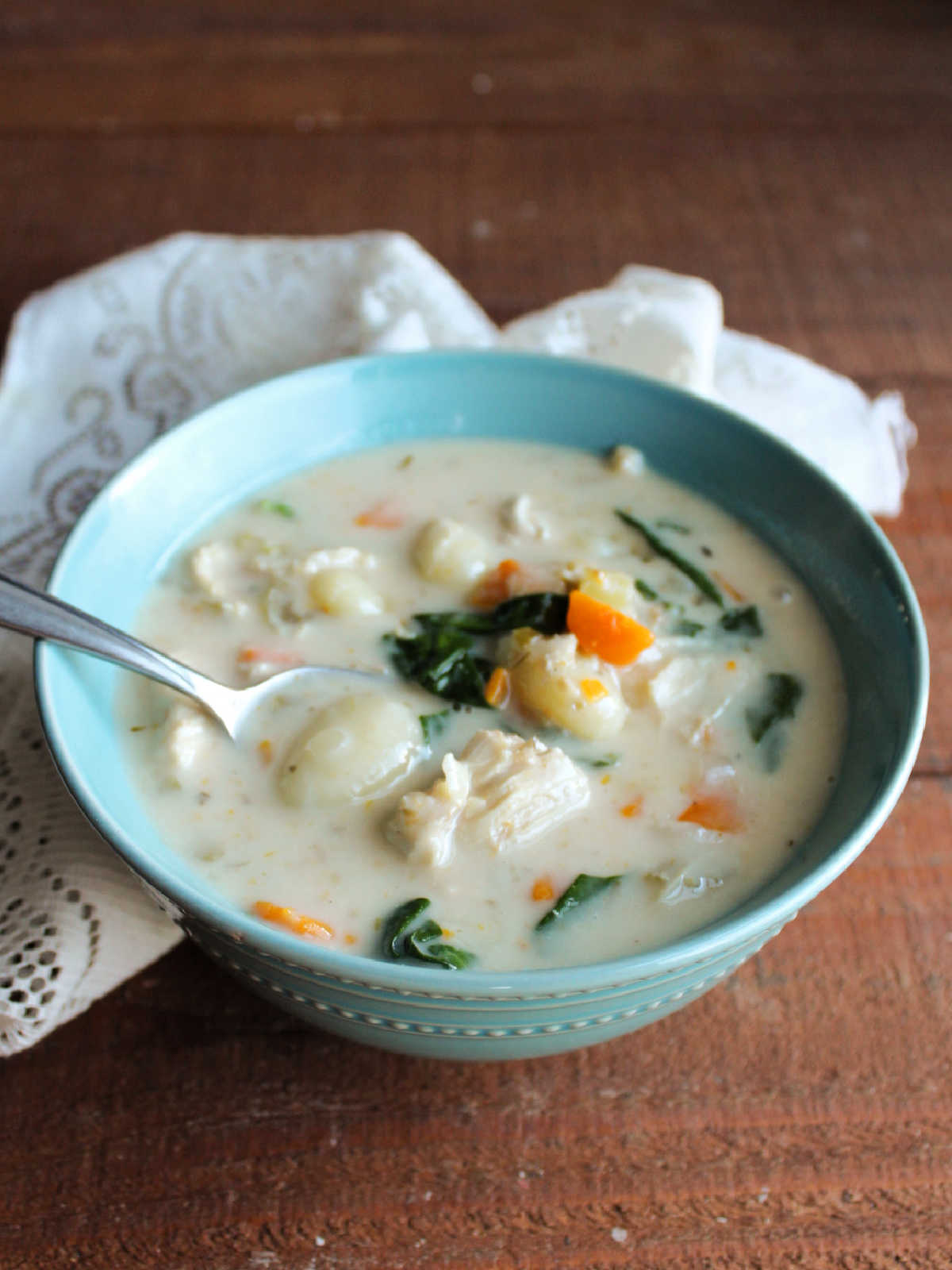 Bowl of chicken gnocchi soup showing the tender gnocchi with plenty of veggies and chicken in a thick, creamy broth.