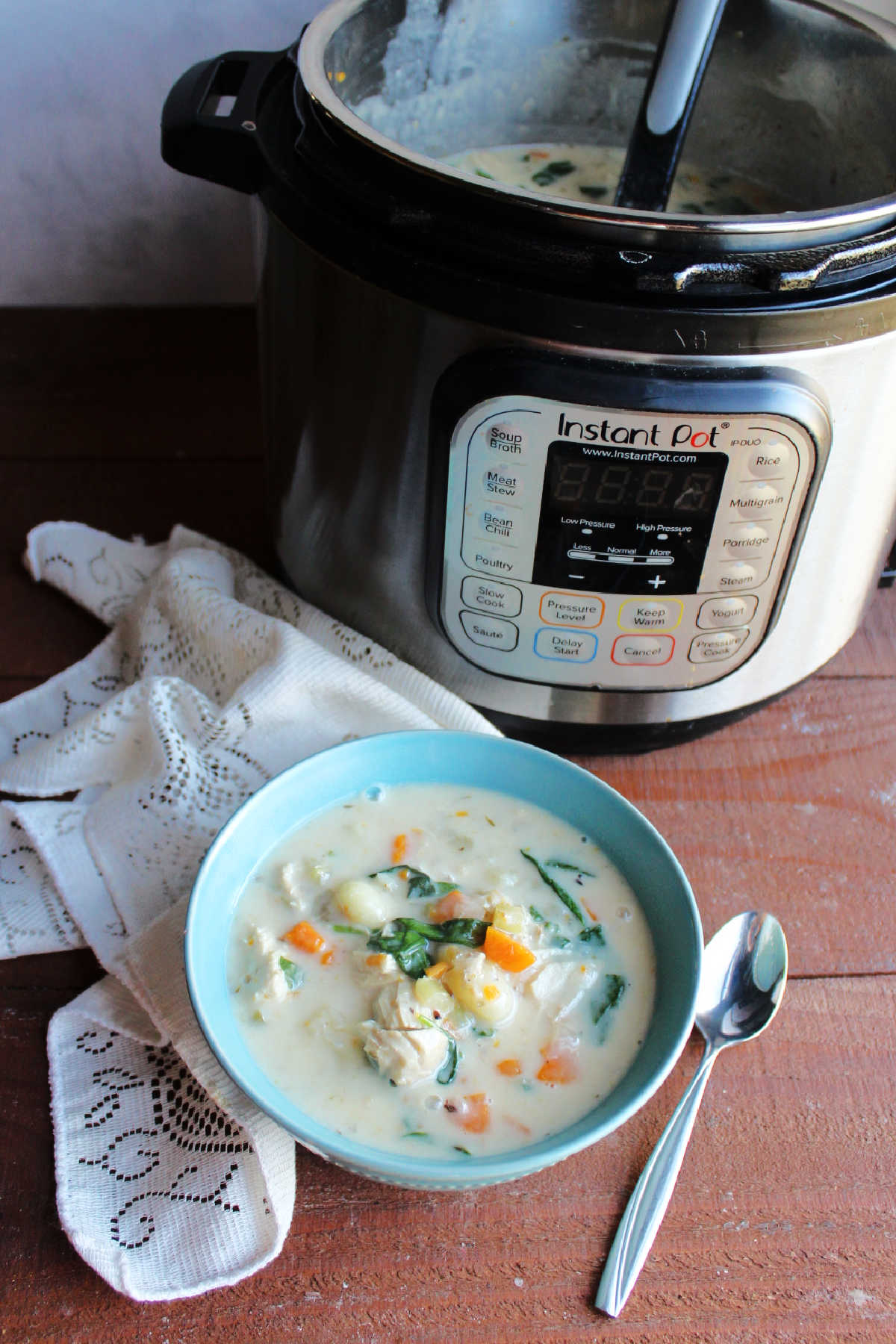 Bowl of creamy chicken gnocchi soup served in front of Instant Pot. 