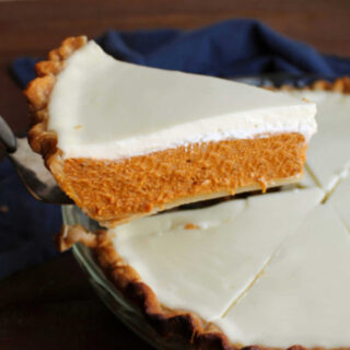 Lifting piece of pie out of pan showing rich condensed milk pumpkin pie layer topped with smooth creamy sour cream topping.