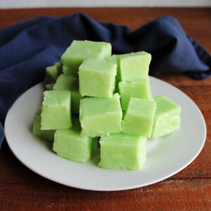 Plate of creamy light green colored lime jell-o fudge squares, ready to be eaten.