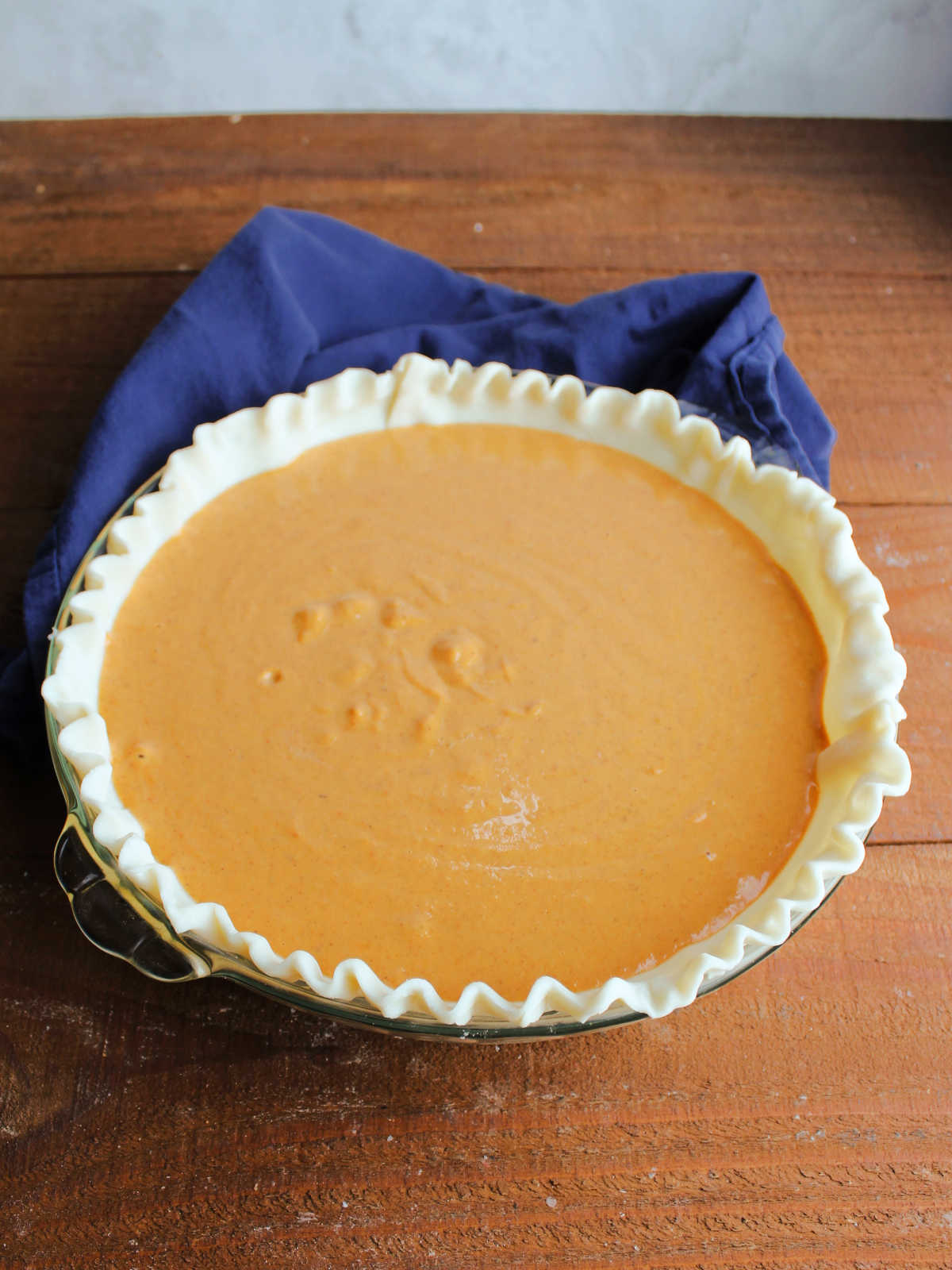Pie dish with raw pie pastry and condensed milk pumpkin pie filling inside. 