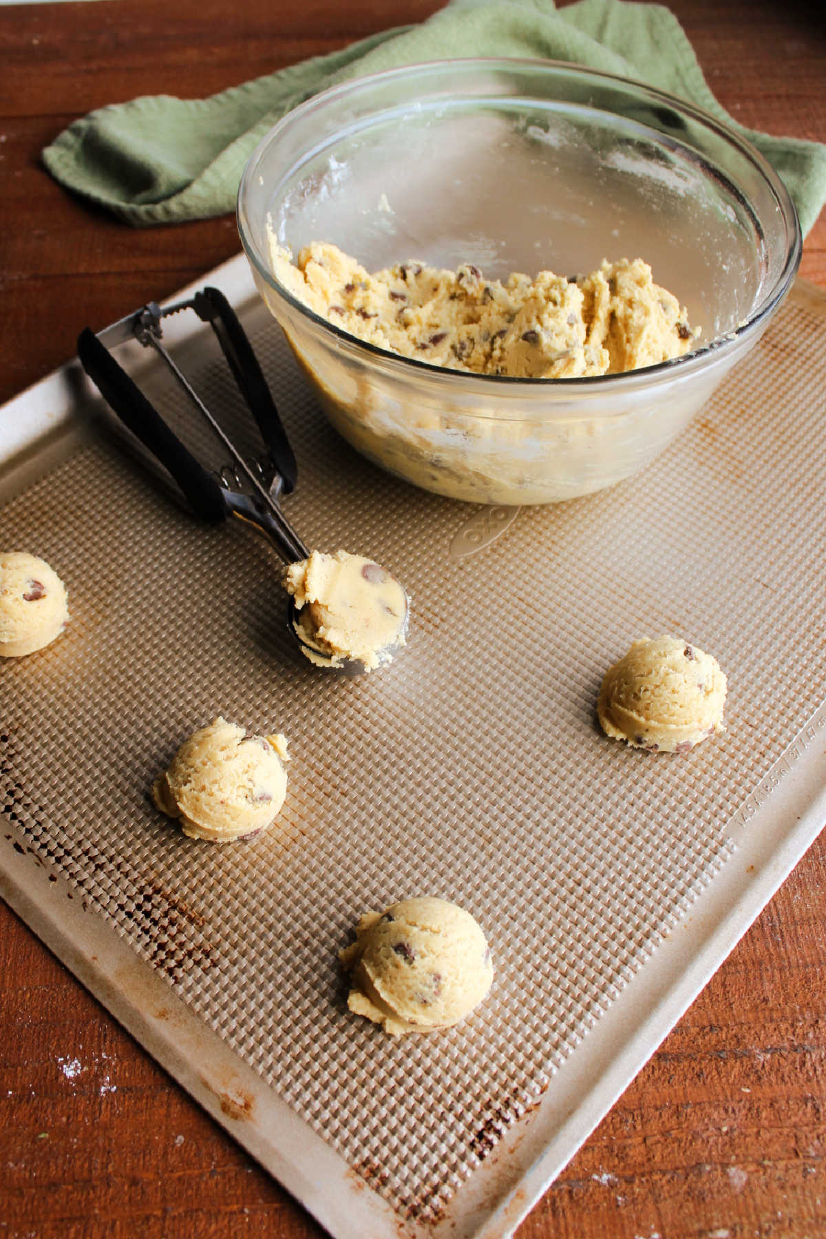 Scooping chilled chocolate chip cookie dough onto cookie sheet to bake.