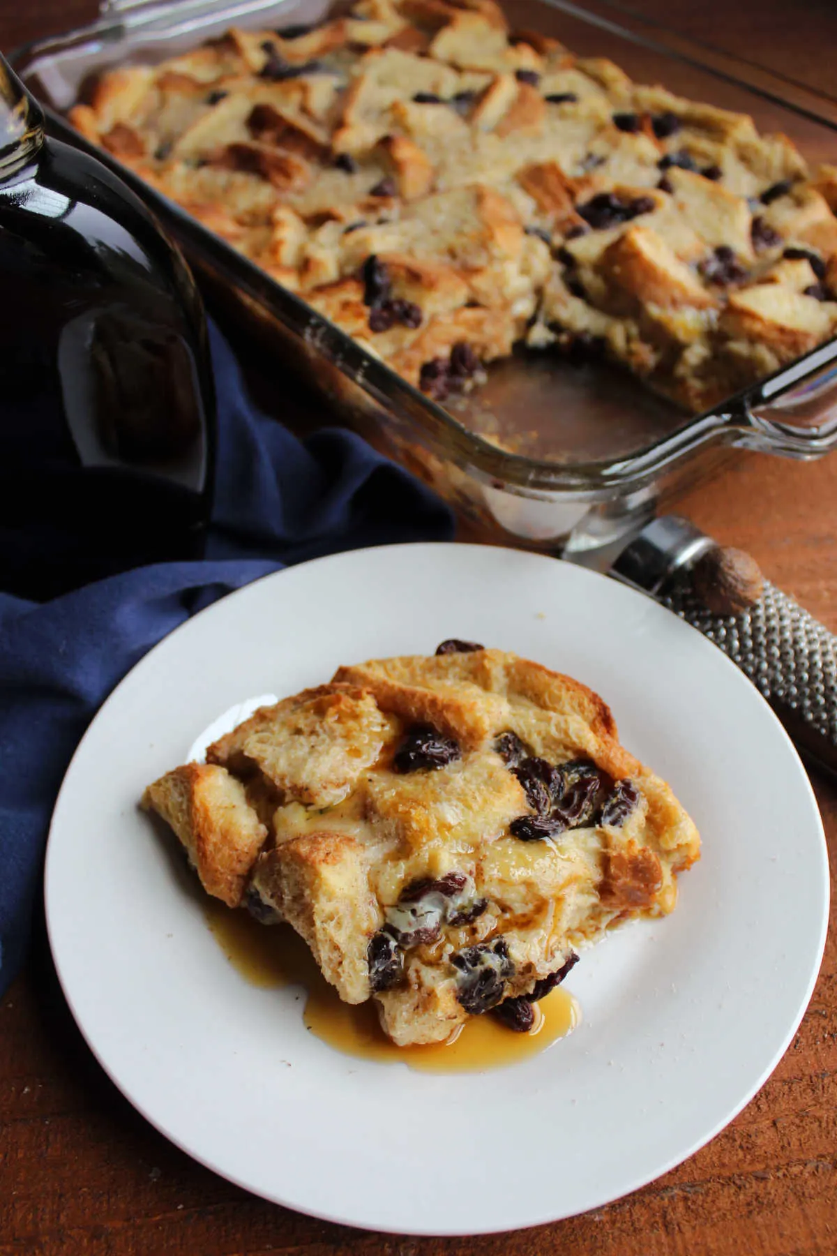 Square of bread pudding with raisins drizzled with a little bit of maple syrup, ready to eat. 