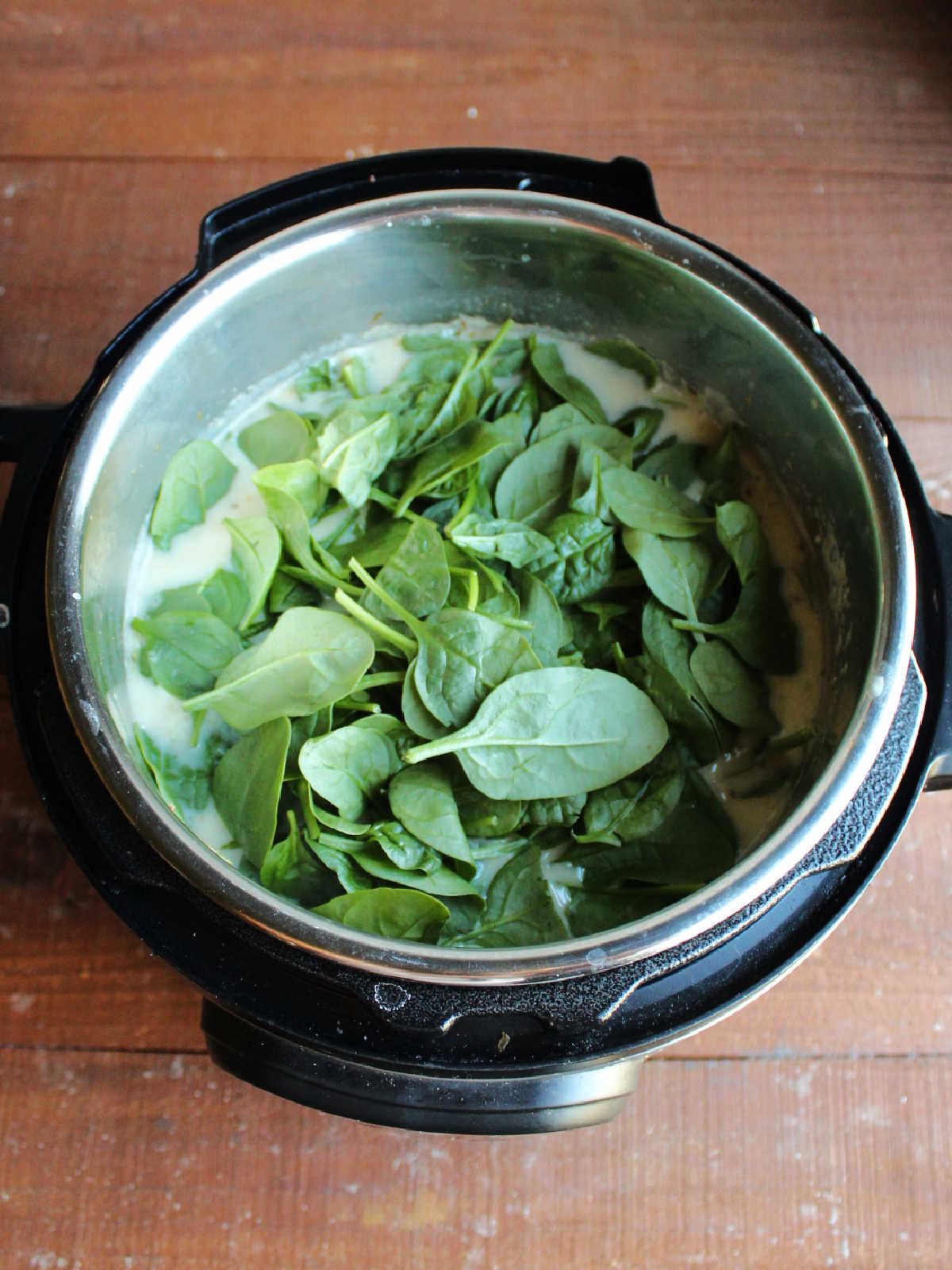 Adding baby spinach to Instant Pot.