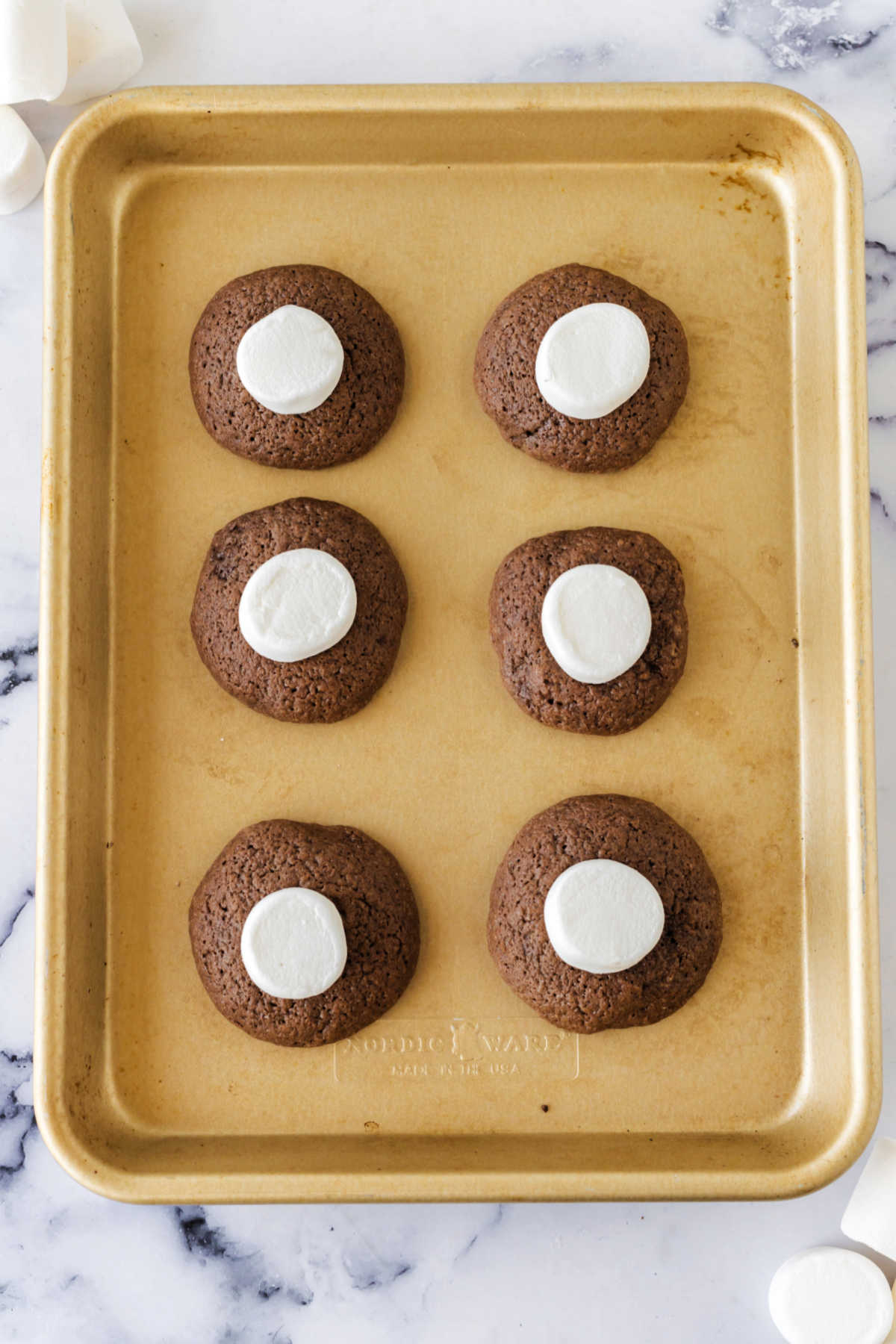 Putting marshmallow halves on partially baked chocolate cookie dough.