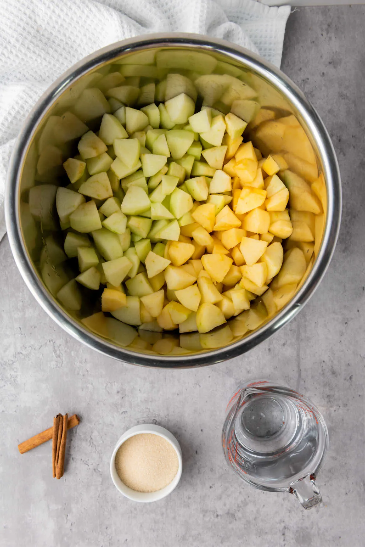 Diced apples in instant pot insert with remaining ingredients nearby.