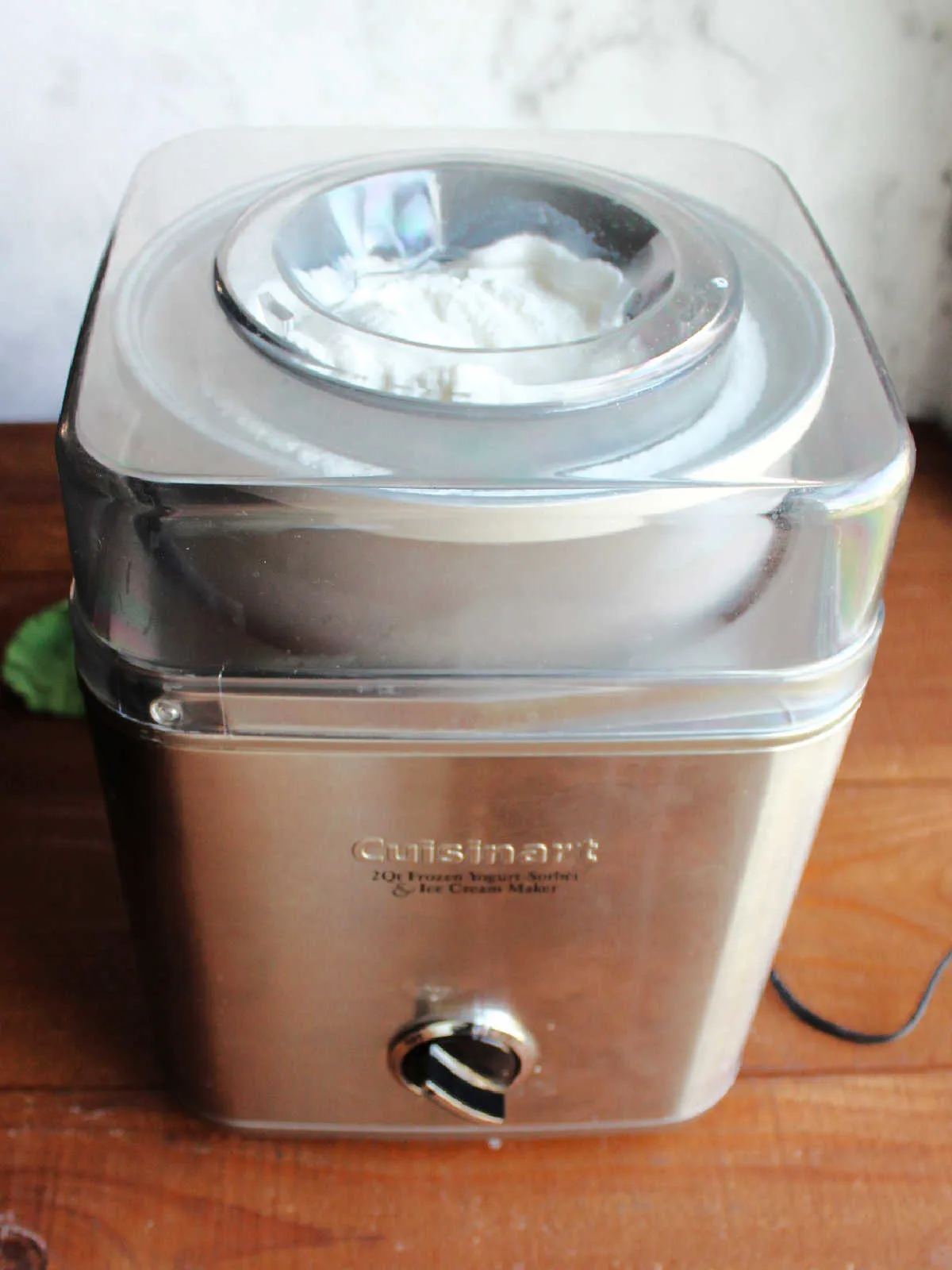 Ice cream maker with churned vanilla ice cream inside, ready to go into storage containers.