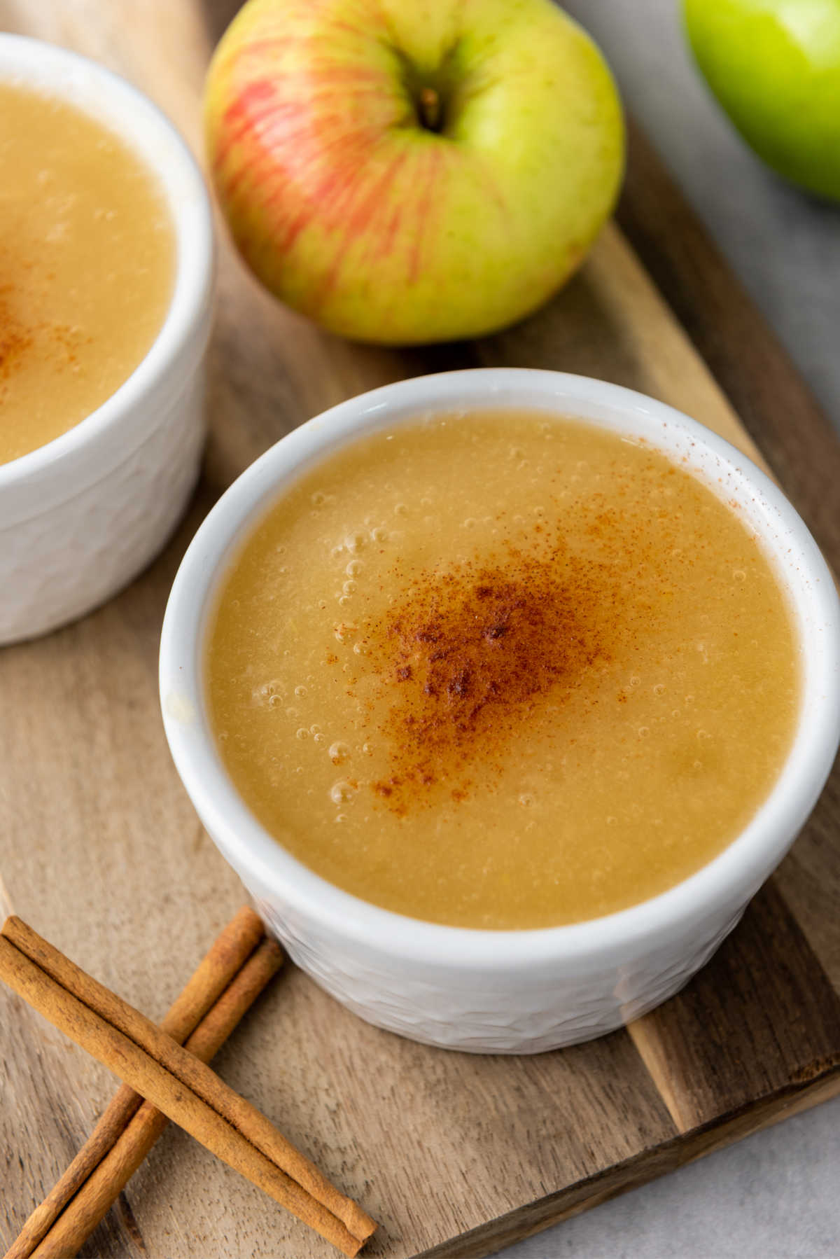 Two bowls of smooth applesauce topped with a little bit of cinnamon, ready to eat.