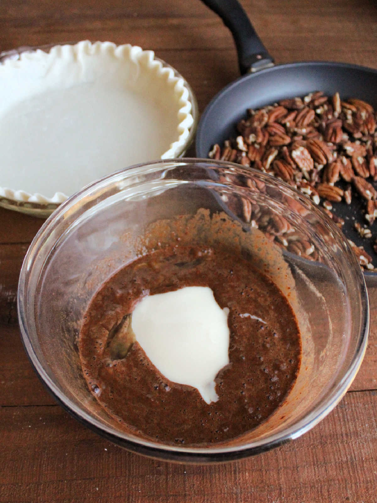 Large mixing bowl with condensed milk poured into chocolate egg mixture, ready to be made into pecanpie filling.