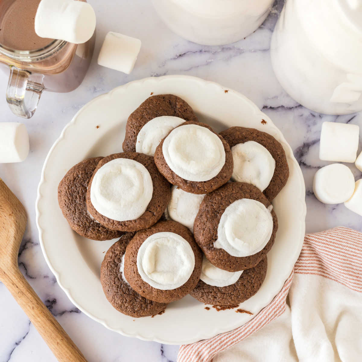 Plate of hot chocolate cookies with melted marshmallows baked onto the top of a soft chocolate cookie.