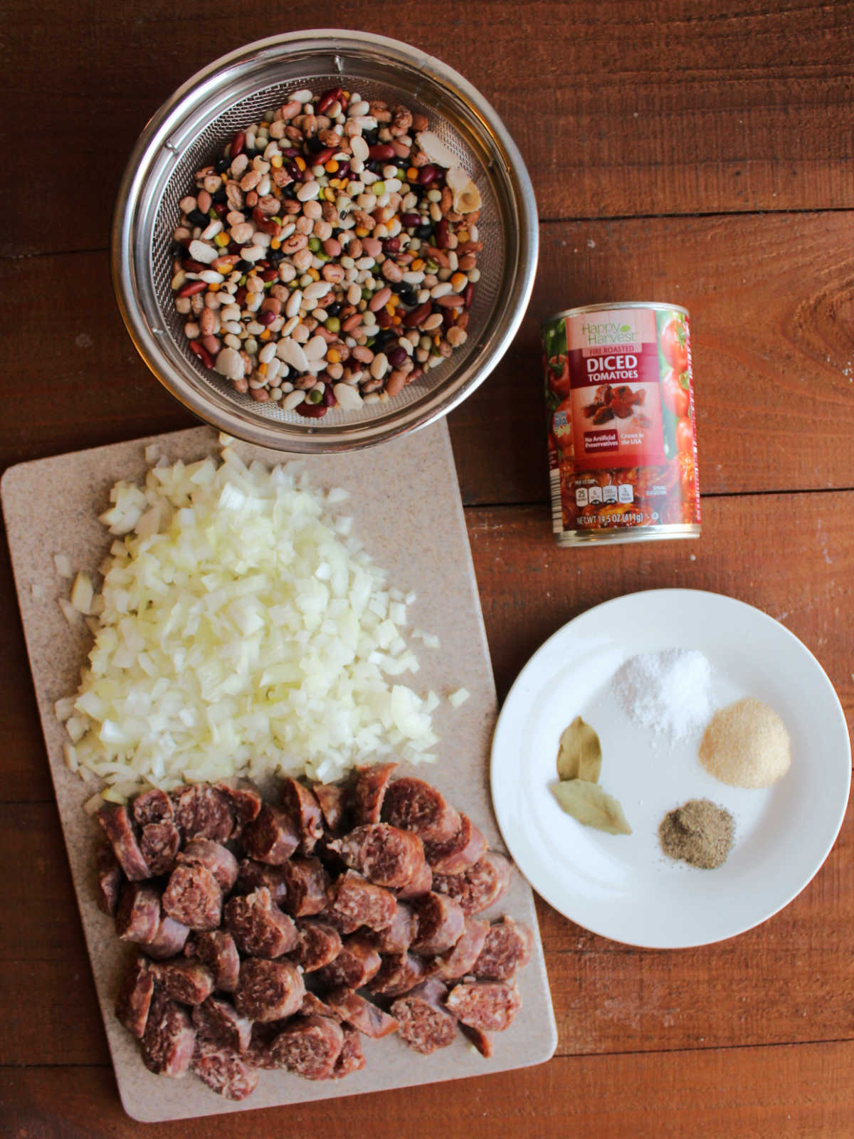 Ingredients including rinsed 16-bean mix, diced onion, sliced smoked sausage, seasonings, and can of fire roasted diced tomatoes ready to be made into Instant Pot bean soup.