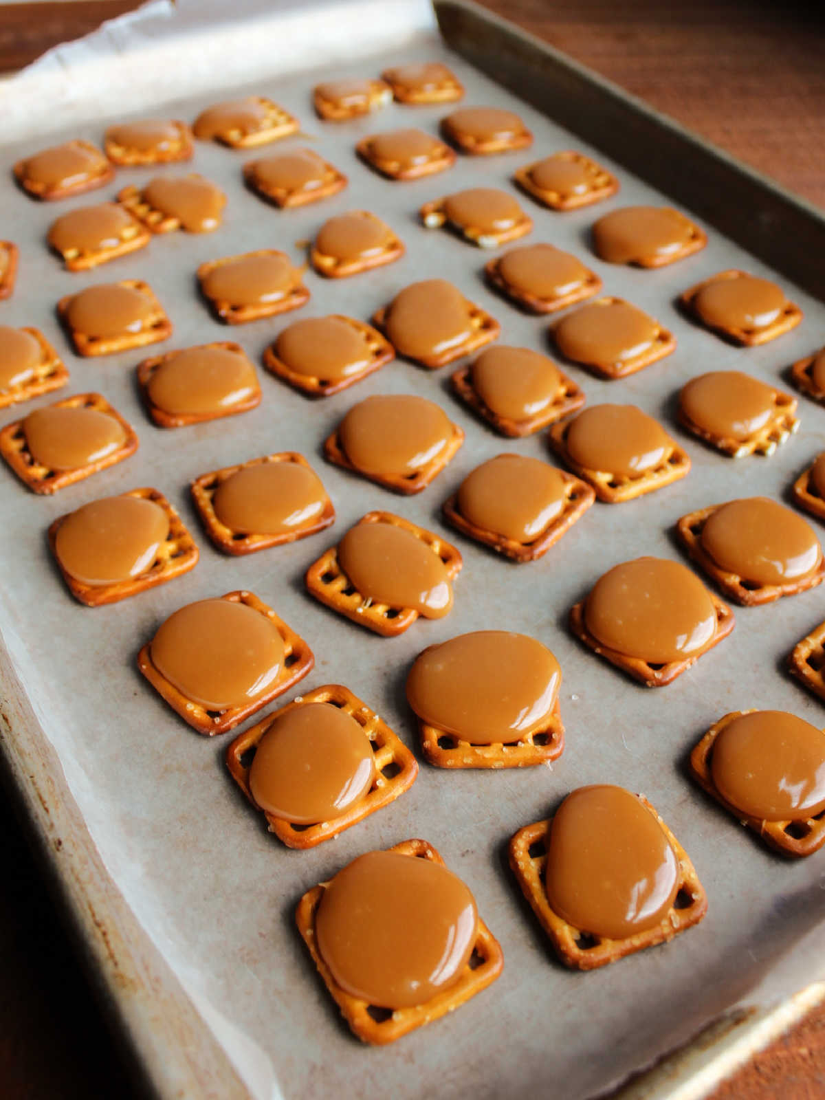 Tray of square pretzels topped with gooey caramel, waiting for chocolate.