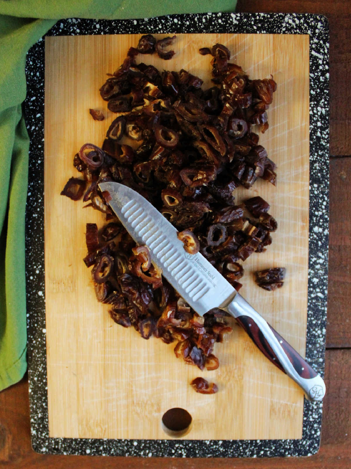Cutting board with chopped dates and a knife.