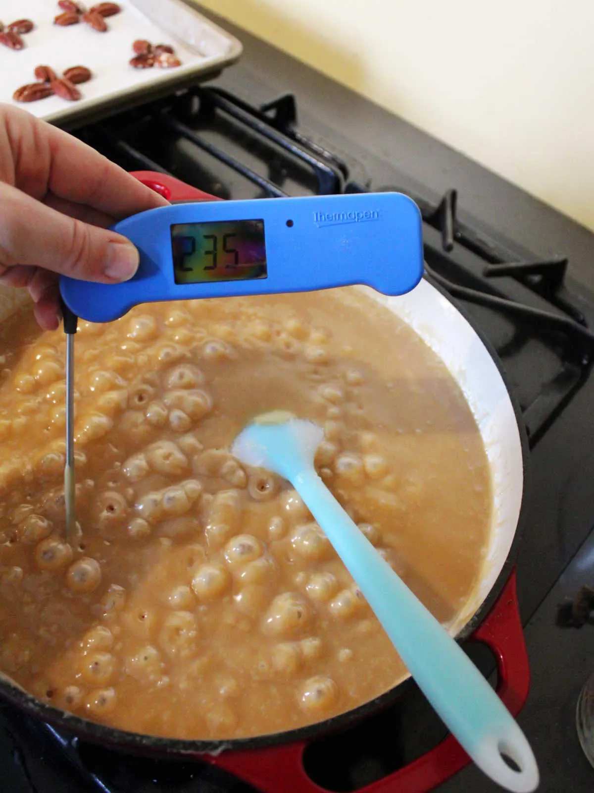 Pan of boiling caramel mixture with instant read thermometer reading 235 degrees Fahrenheit. 
