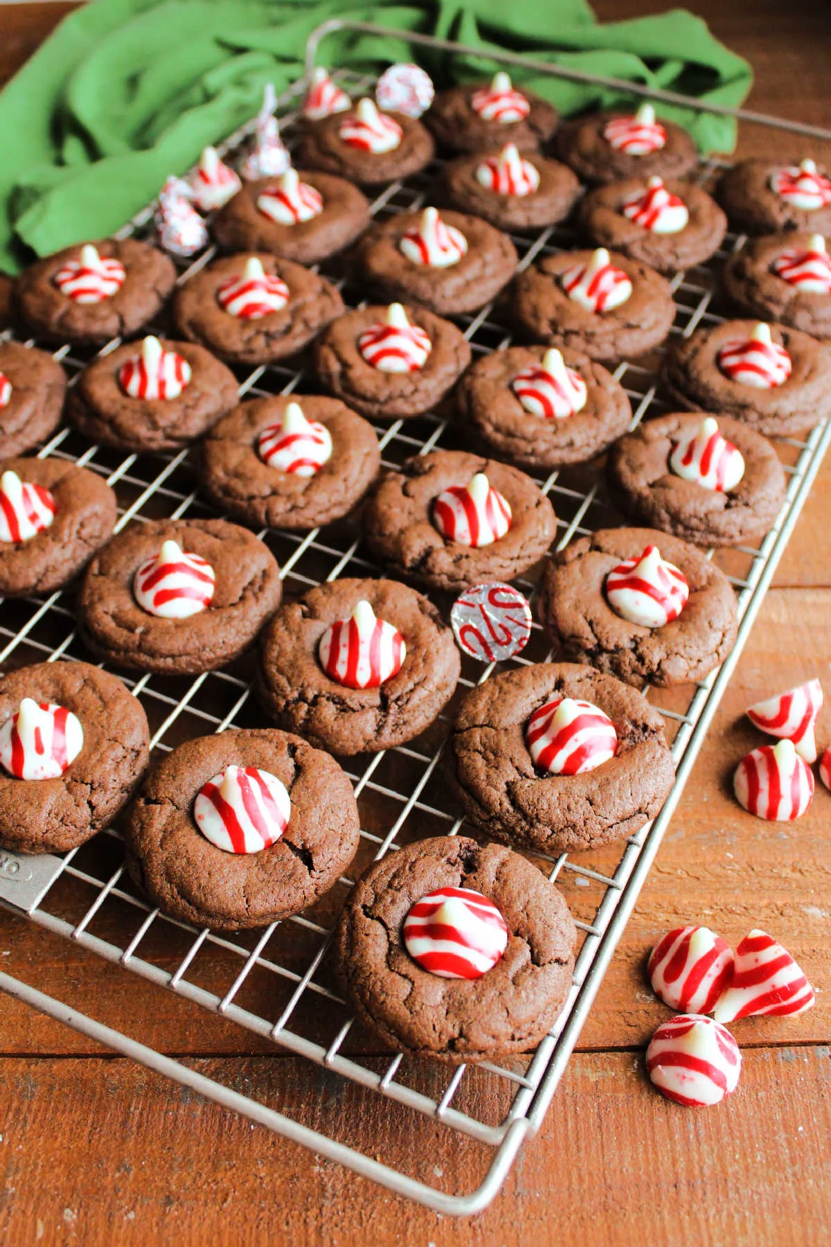 Cooling rack of chocolate peppermint blossom cookies with candy cane kisses in the center.