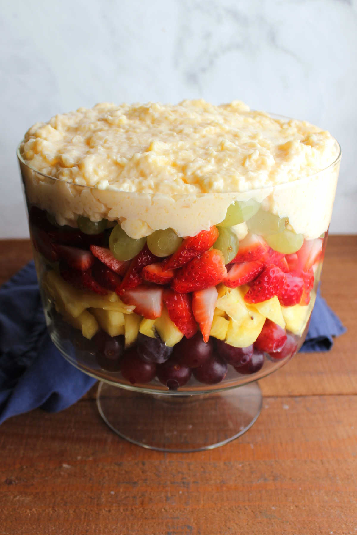 Pudding mixture layered on top of fresh fruit in trifle bowl.