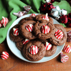 Plate of chocolate blossom cookies with red and white striped peppermint kisses in the center.