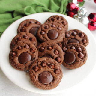 Plate with chocolate paw print cookies featuring rich chocolate cookie base topped with chocolate chips and chocolate candy to look like a paw print.